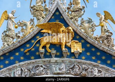 Angels and the lion on the top of the Basilica di San Marco facade (Saint Mark`s Basilica) in Venice, Italy. The winged lion is a symbol of Venice. Stock Photo